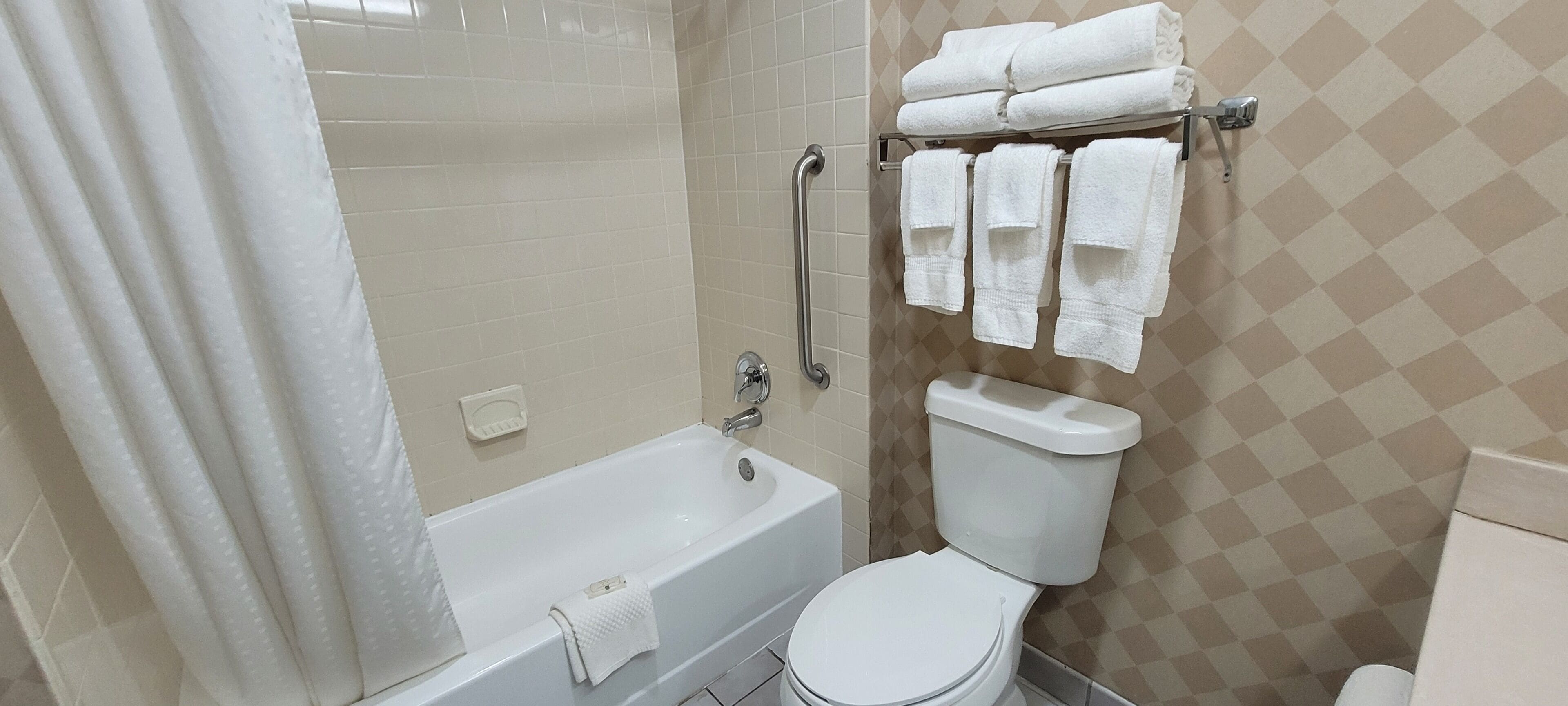 A bathroom with a bathtub, toilet, and a towel rack with towels.