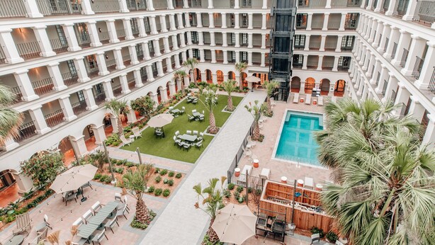 Ein mehrgeschossiges Hotel mit Innenhof, Außenbereich und Pool.
