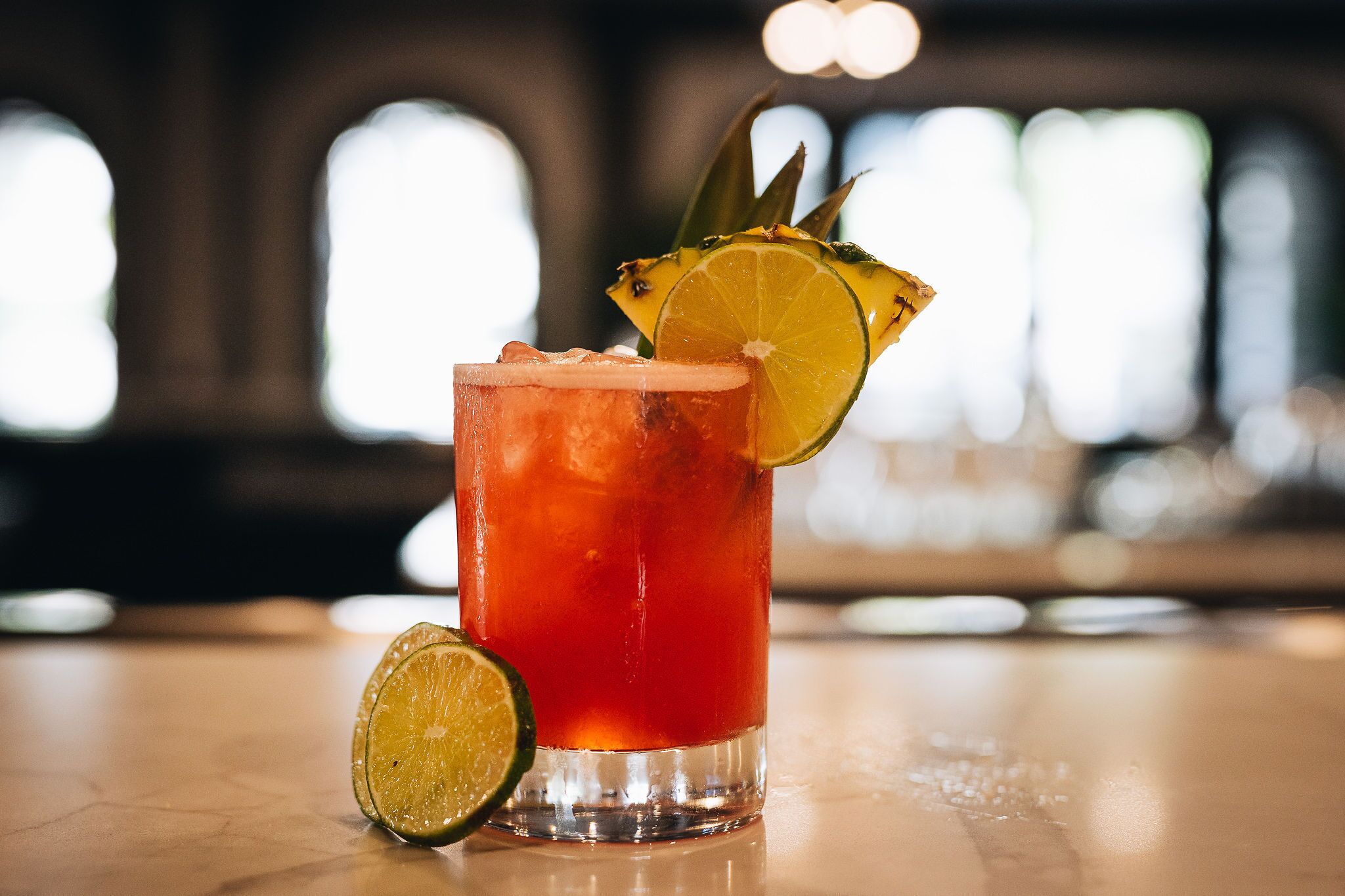 A cocktail with a lime garnish on a bar counter.