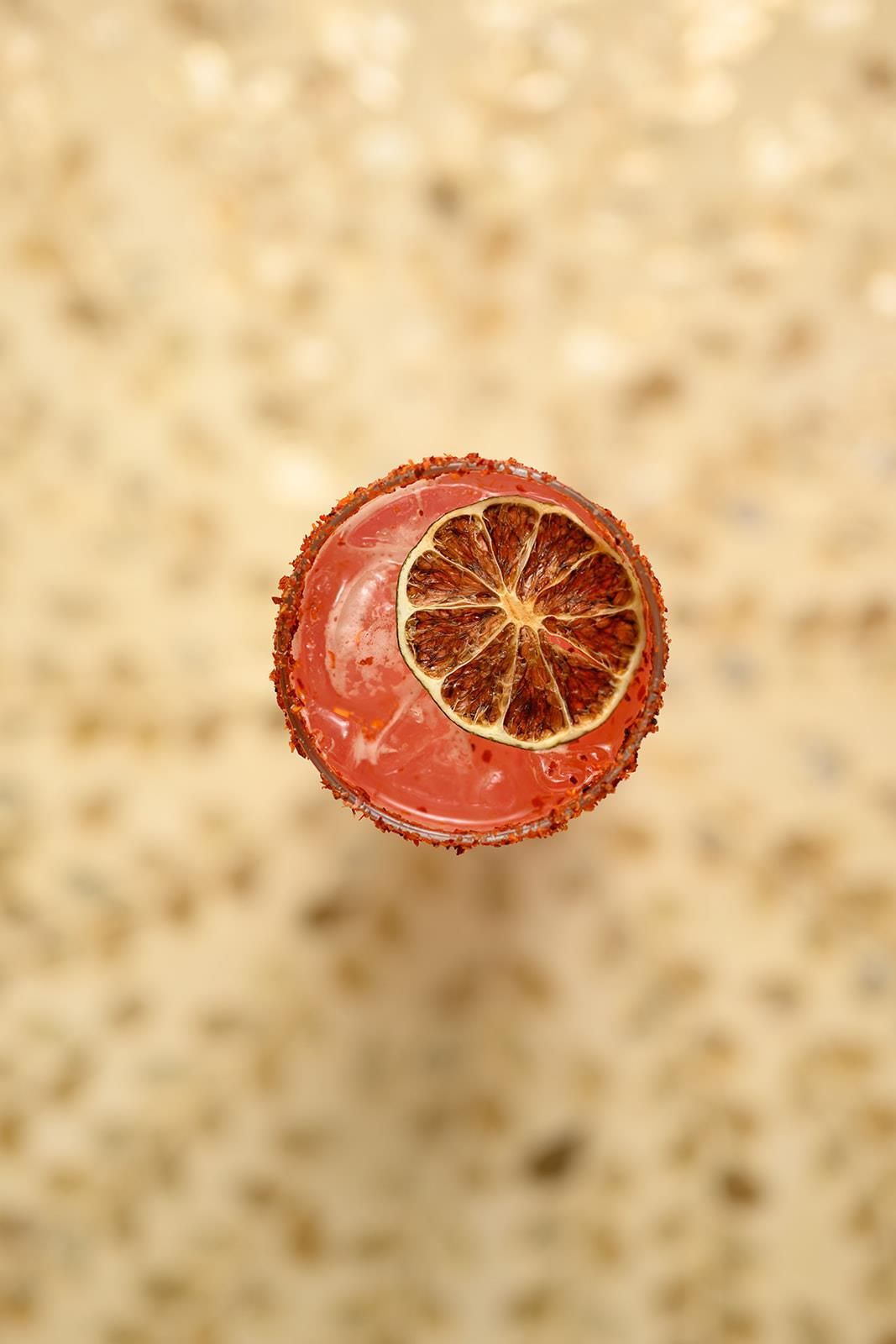 A cocktail with a salted rim and a dried citrus slice garnish.