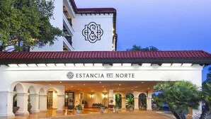 Ein Hotel mit weißer Fassade, rotem Dach und dem Schriftzug 'ESTANCIA DEL NORTE' über dem Eingang.