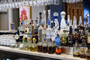 Una barra con diferentes botellas de licores y vasos.