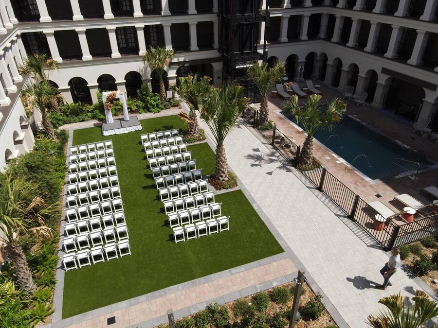 Ein Innenhof mit Reihen weißen Stühlen, einem Pool und einem Gebäude mit mehreren Balkonen.