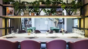 Een vergadertafel met stoelen, omringd door potplanten, in een modern interieur met uitzicht buiten.