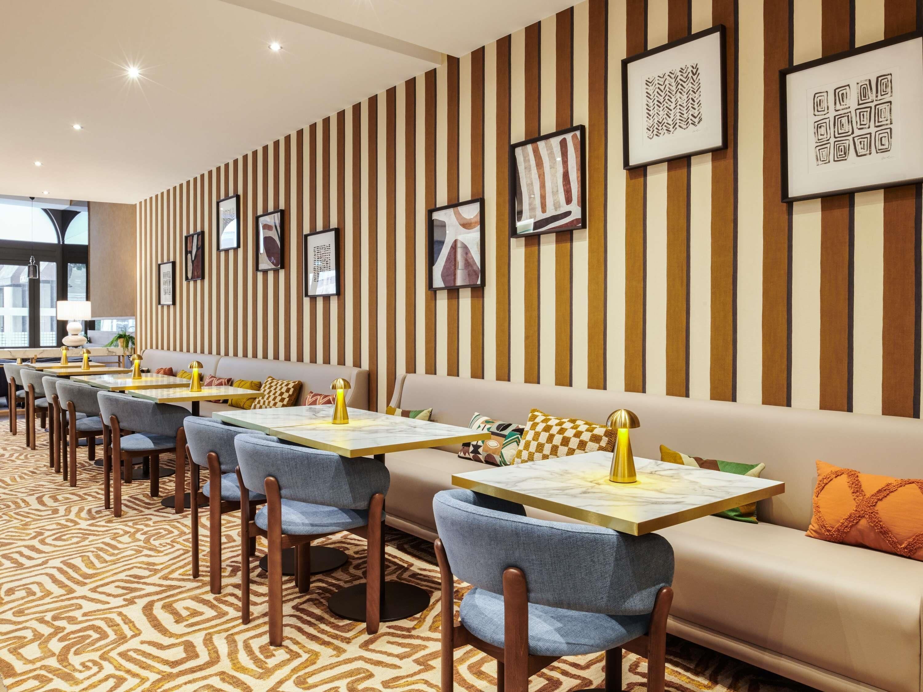 A restaurant with striped walls, framed artwork, and a patterned carpet.