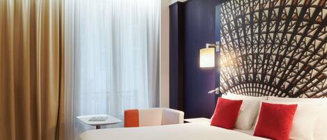 A hotel room with a large bed, a small table, and a decorative wall.