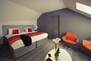 A modern hotel room with a large bed, two chairs, a small table, and a door. - Mercure Nantes Centre Grand Hotel (Nantes)
