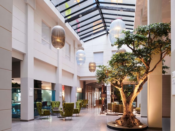 A spacious indoor area with a central tree, modern furniture, and hanging spherical light fixtures.