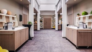Een moderne hotel lobby met een centrale gang, houten kasten en een hoge plafond met dakramen.