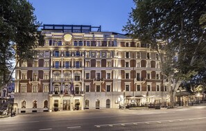 A multi-story hotel with a grand entrance, multiple balconies, and a well-lit facade.