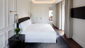 Une chambre d’hôtel moderne dotée d’un grand lit, d’une table de chevet agrémentée d’un vase de fleurs, d’un téléviseur à écran plat fixé au mur et offrant une vue sur le balcon extérieur.