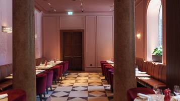A restaurant with a checkered floor, red upholstered booths, and a central wooden door.