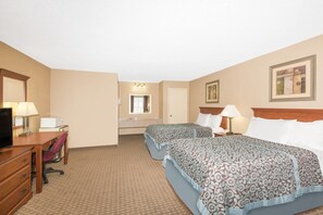 A hotel room with two beds, a desk, a chair, a television, and a bathroom.
