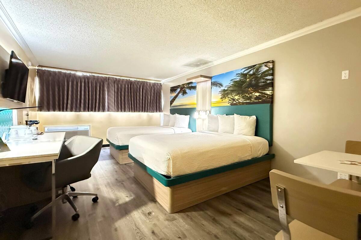 Hotellihuone, jossa on sänky, työpöytä, tuoli, televisio ja taulu seinällä.