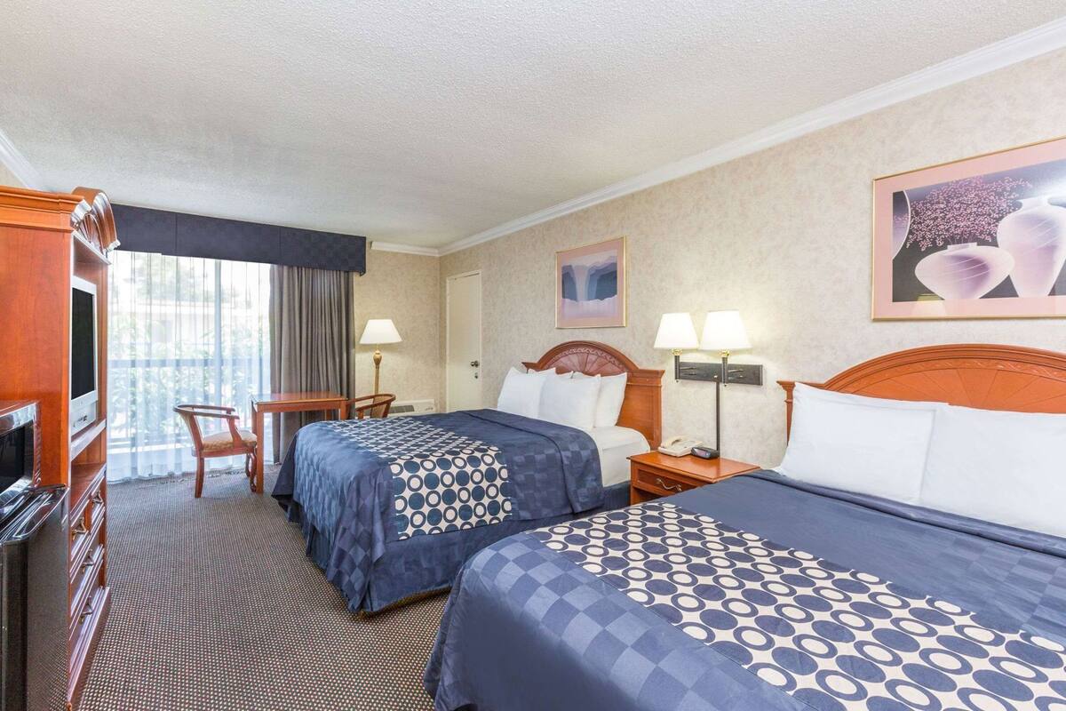Hotellihuone, jossa on kaksi sänkyä, televisio, työpöytä ja tuoli.