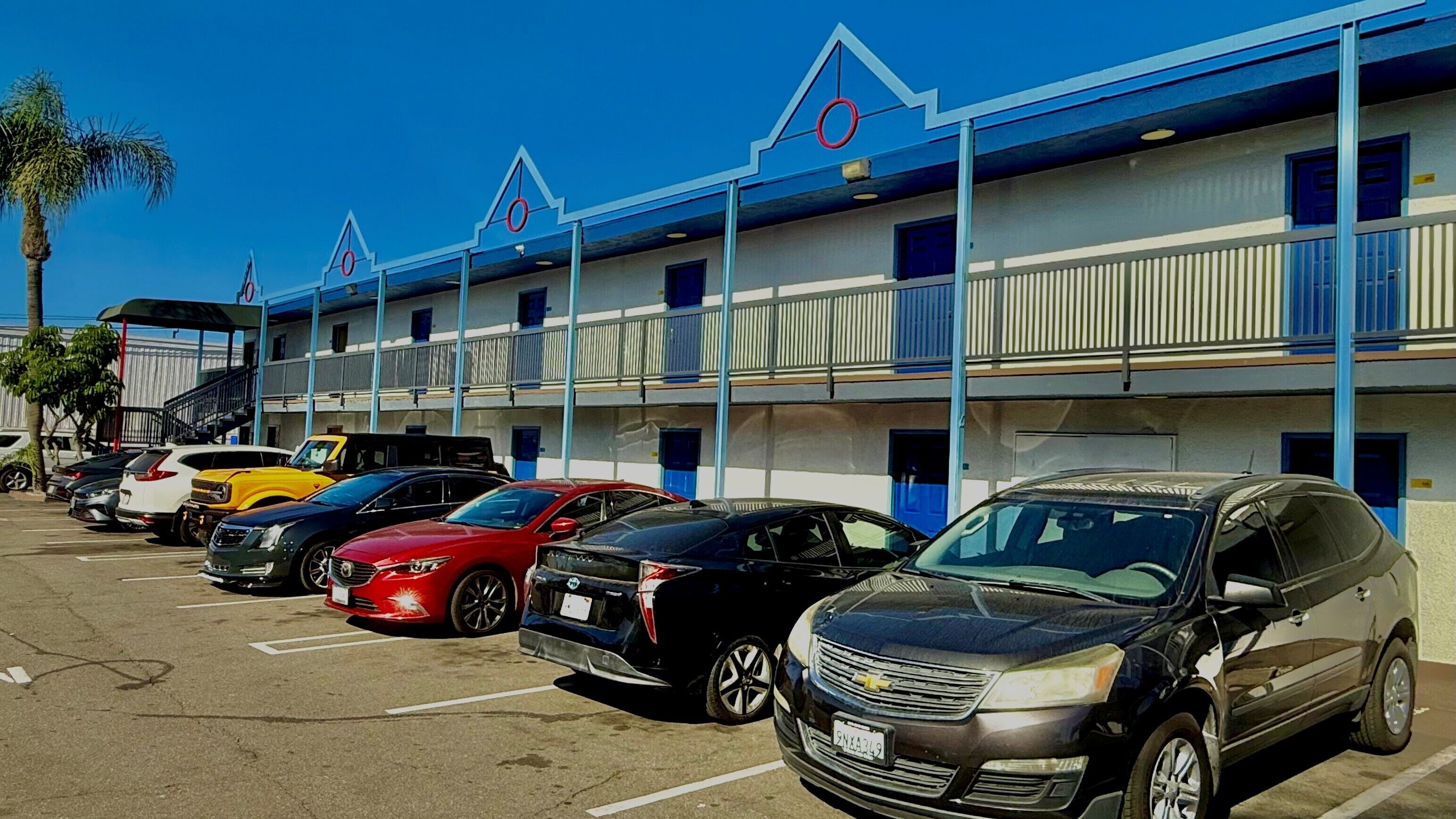 Un motel con diversi posti auto e un'autofila parcheggiata davanti.