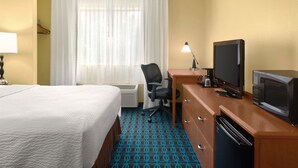 A hotel room with a bed, a desk with a television, a chair, and a desk lamp. - AmeriVu Inn and Suites Grand Forks (Grand Forks)