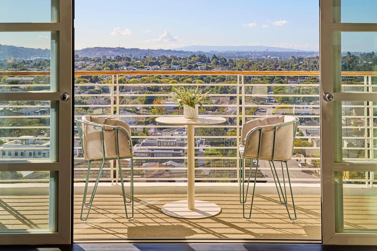 A balcony with a table and chairs, offering a view of a cityscape.