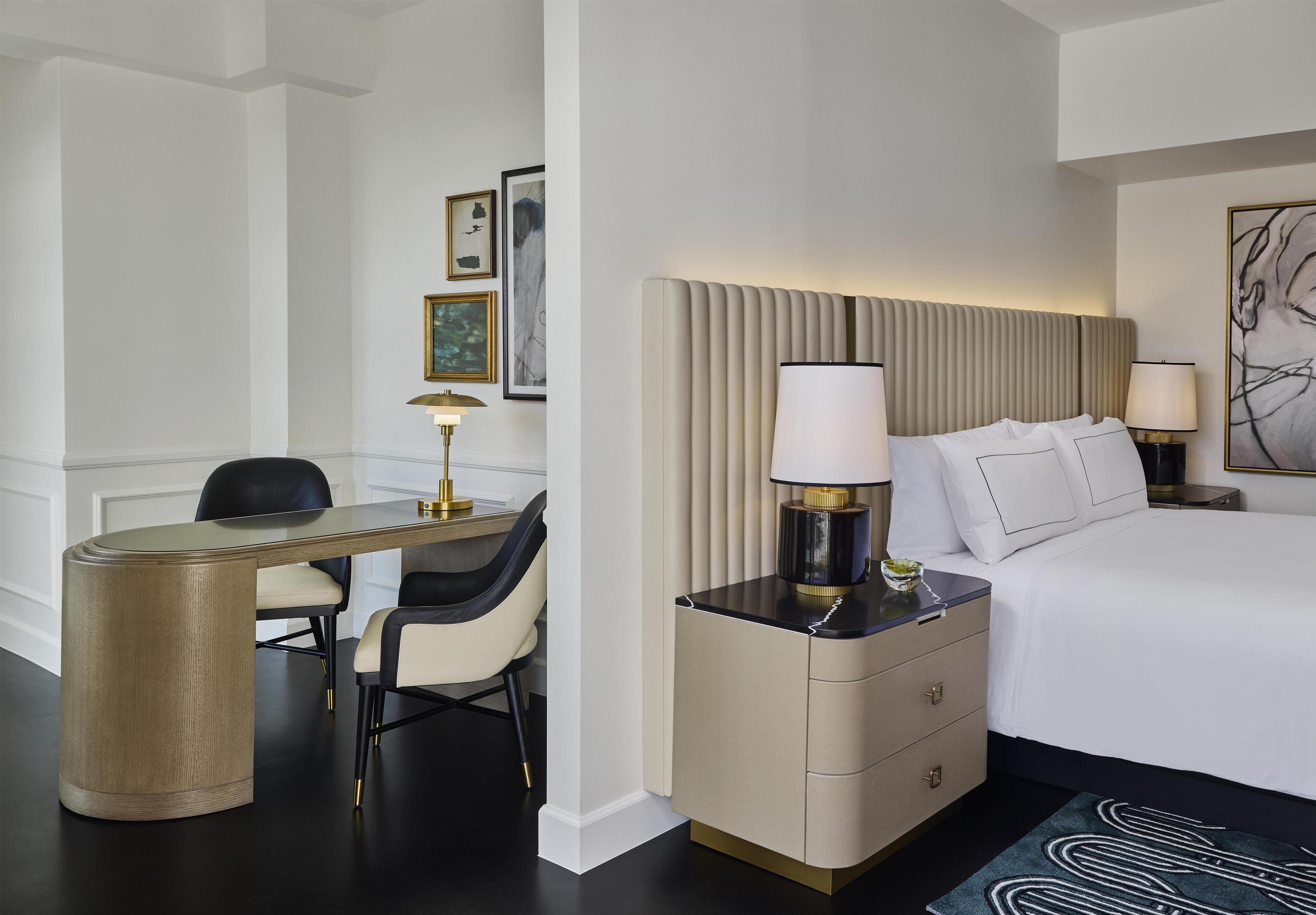 Une chambre d’hôtel comprenant un lit, un bureau, une chaise, une table de chevet et une lampe.