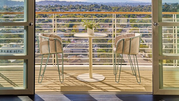 A balcony with a table and two chairs, offering a city view. - Cameo Beverly Hills, LXR Hotels & Resorts (Los Angeles)