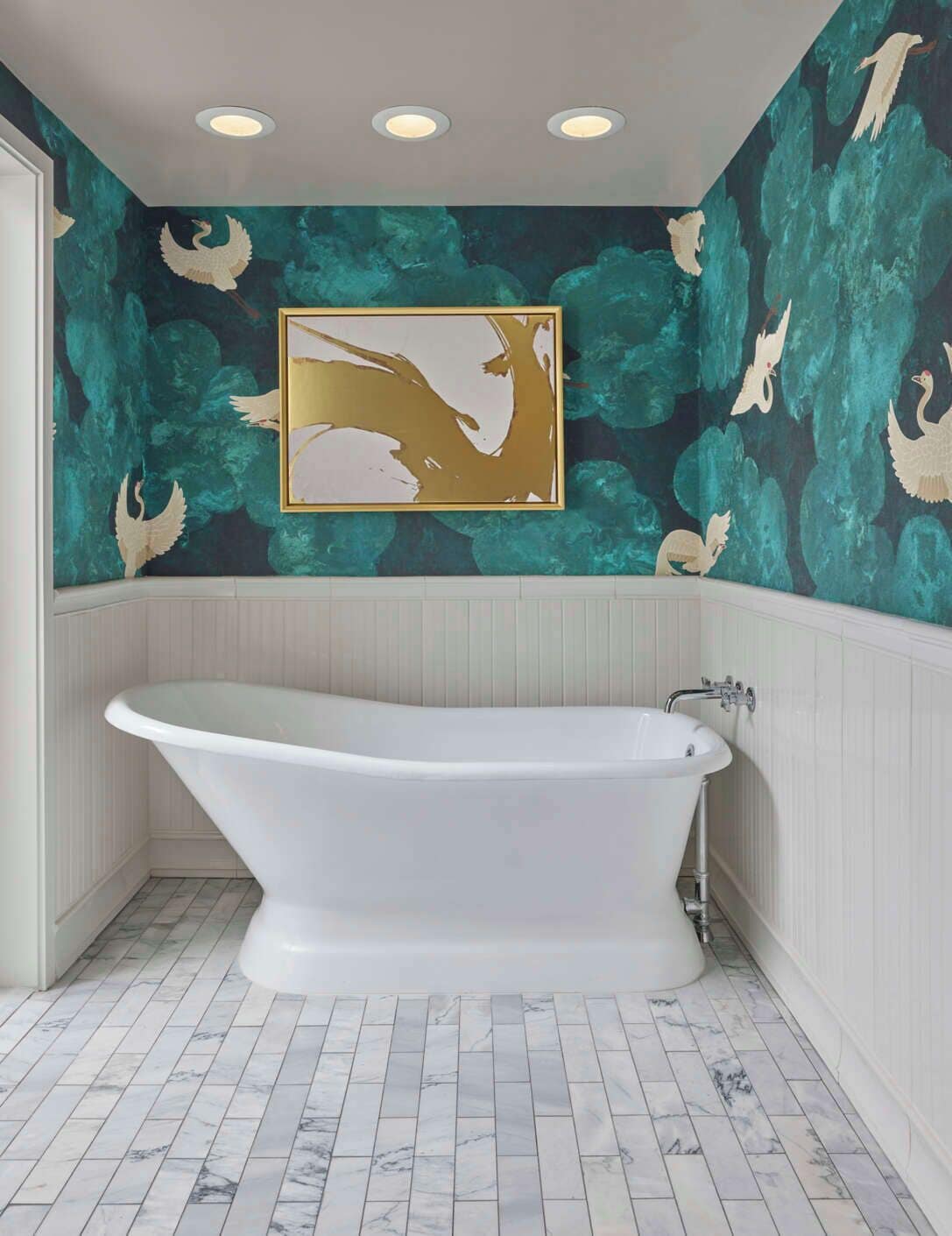 A bathroom with a freestanding bathtub, a wall-mounted painting of swans, and a teal patterned wall.