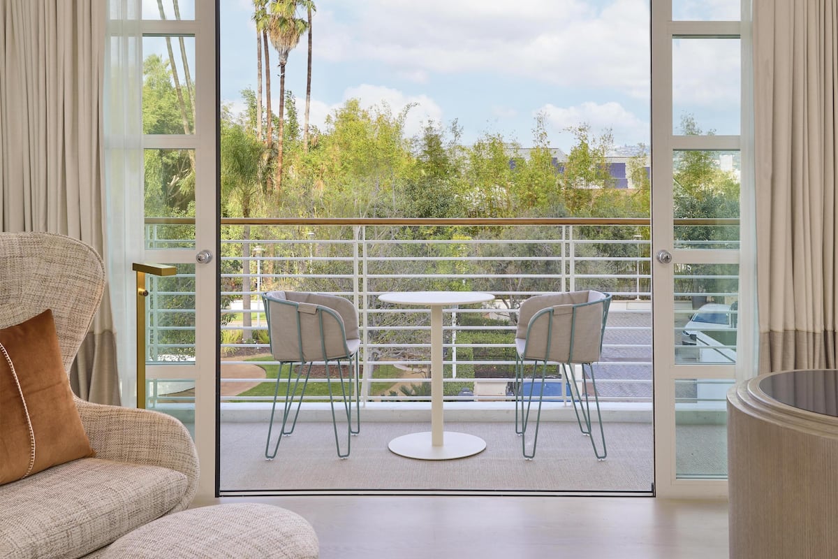 A balcony with a glass railing, two chairs, and a small table.