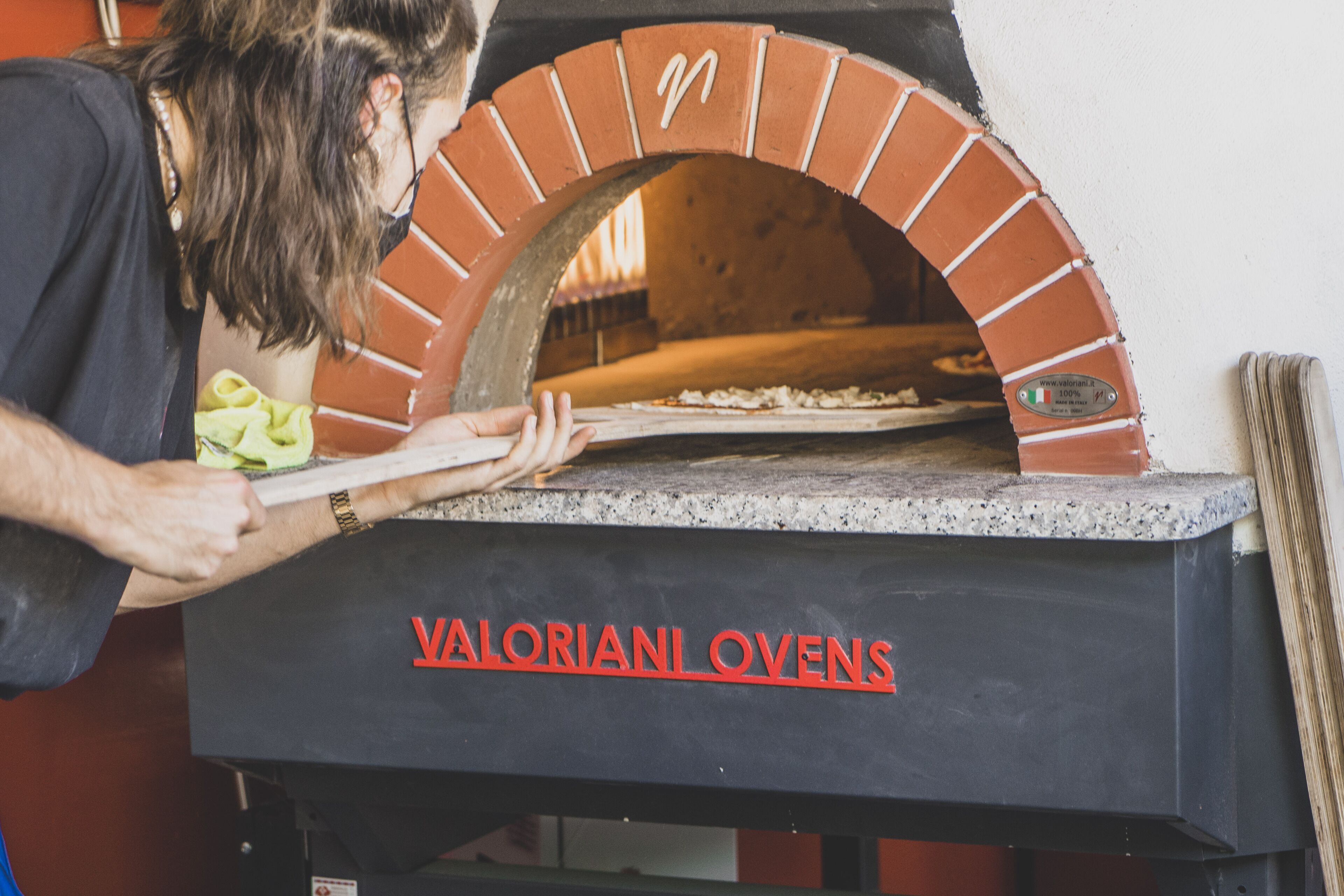A person using a brick oven to bake pizza.