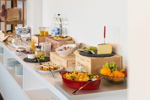 A buffet table with various food items, including fruits, cheese, and desserts.