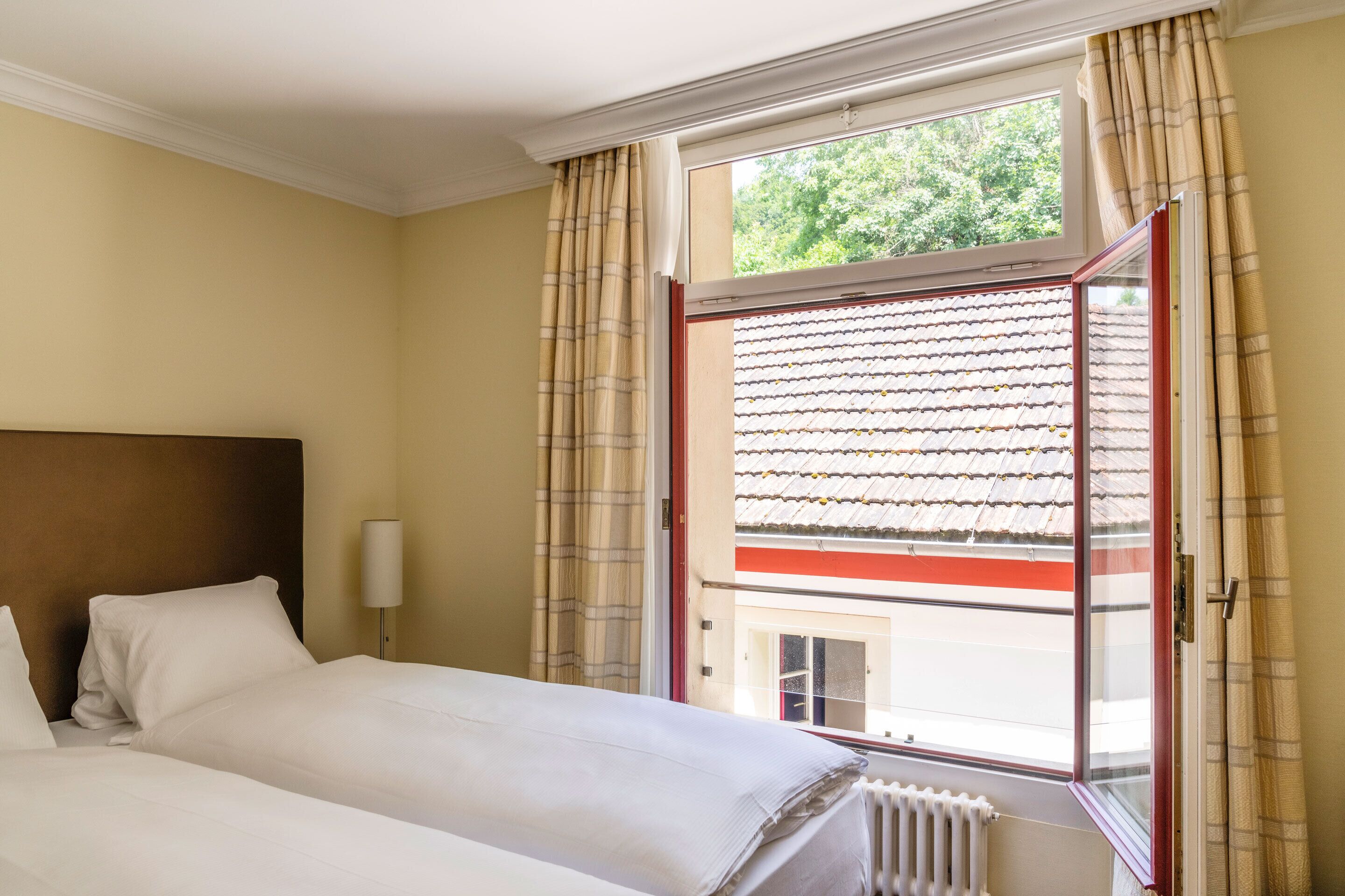 Een hotelkamer met een bed, een raam met gordijnen en uitzicht op de omgeving.