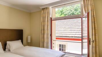 Een hotelkamer met een bed, een raam met gordijnen en uitzicht op de omgeving.