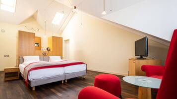 Un dormitorio moderno con cama, televisión y sillas rojas.