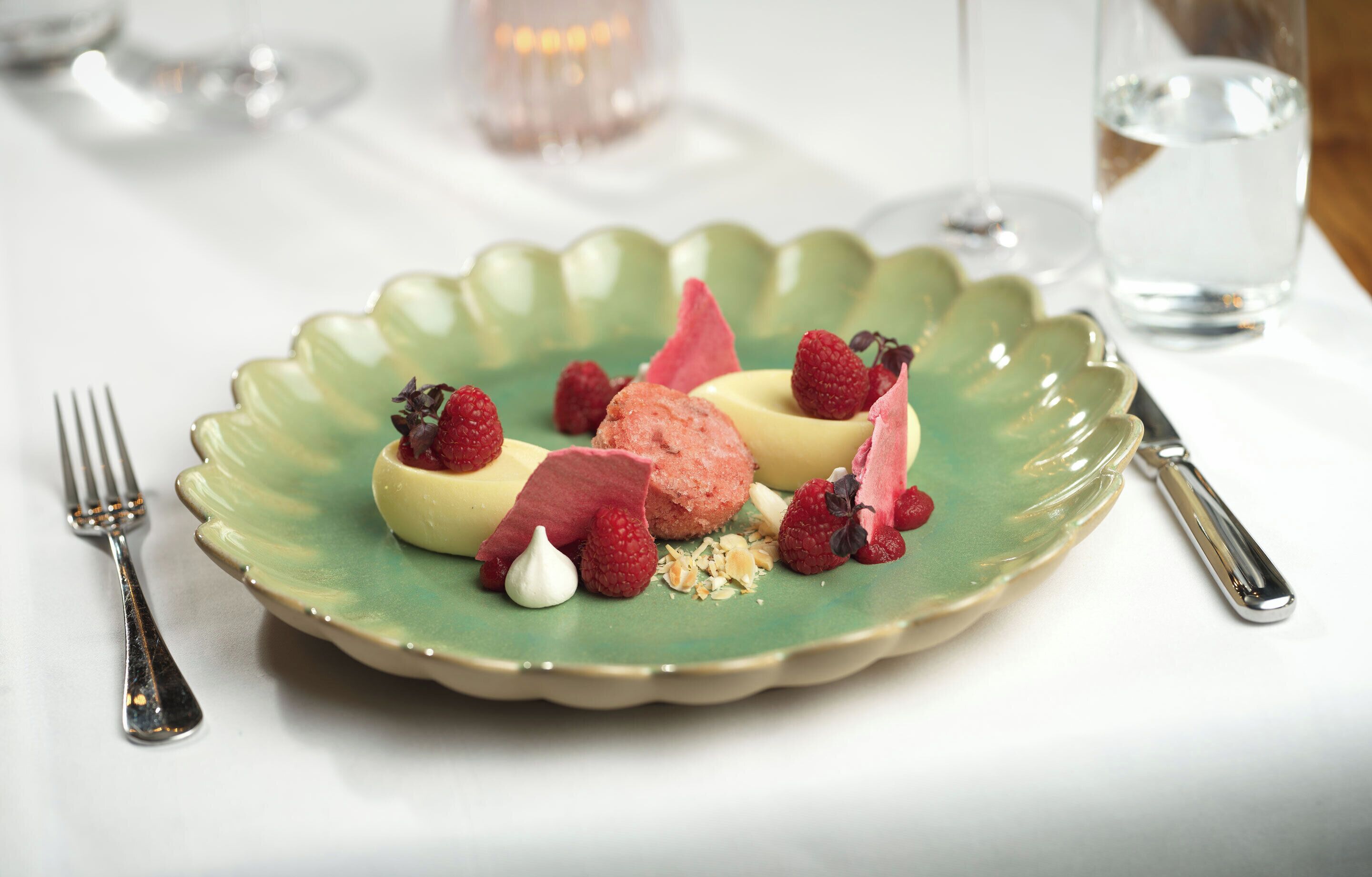 Eine Desserttasse mit Erdbeeren und Schlagsahne auf einer grünen Keramiktasse.