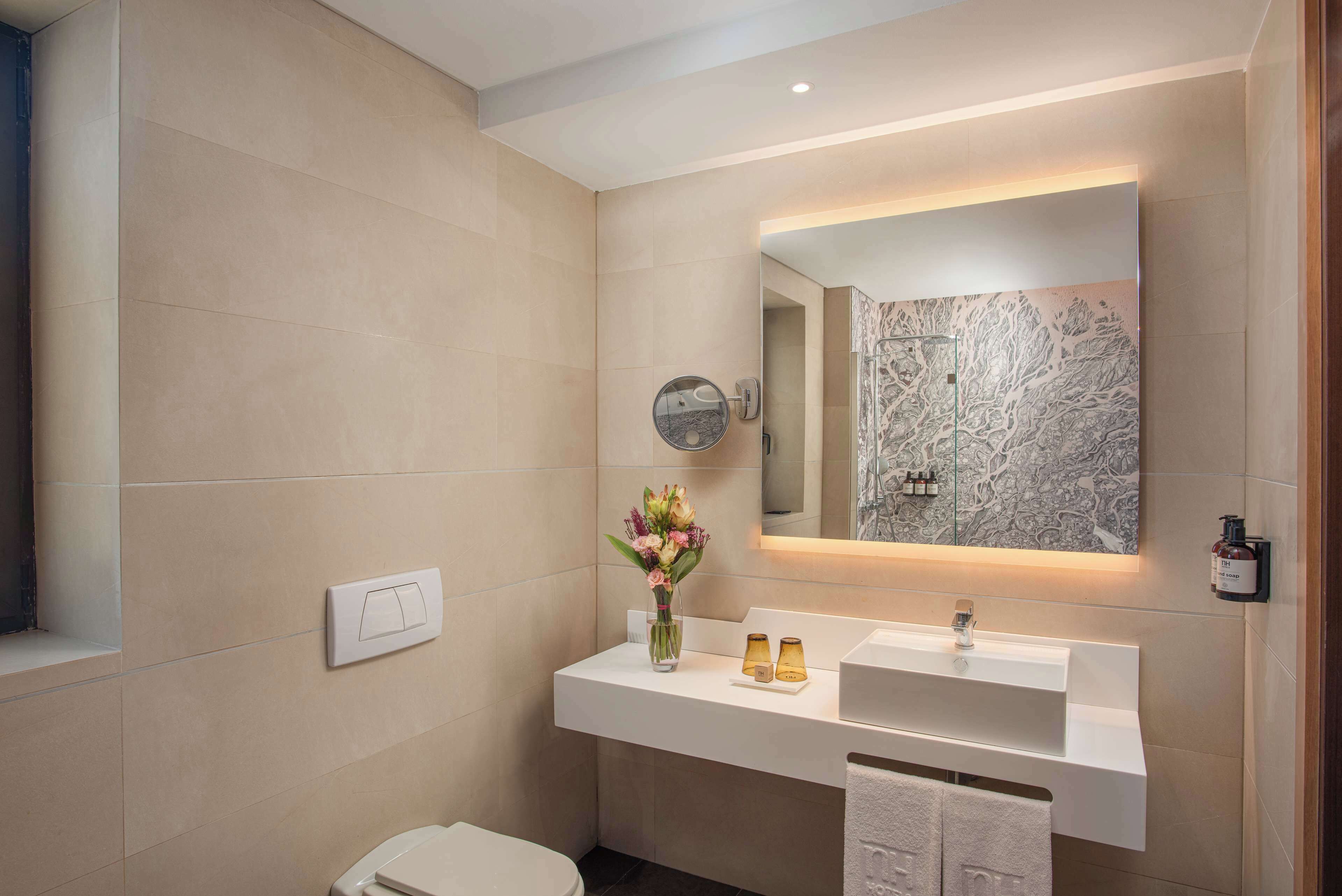 Un baño moderno con un tocador blanco, un espejo grande y una salpicadera de mármol.