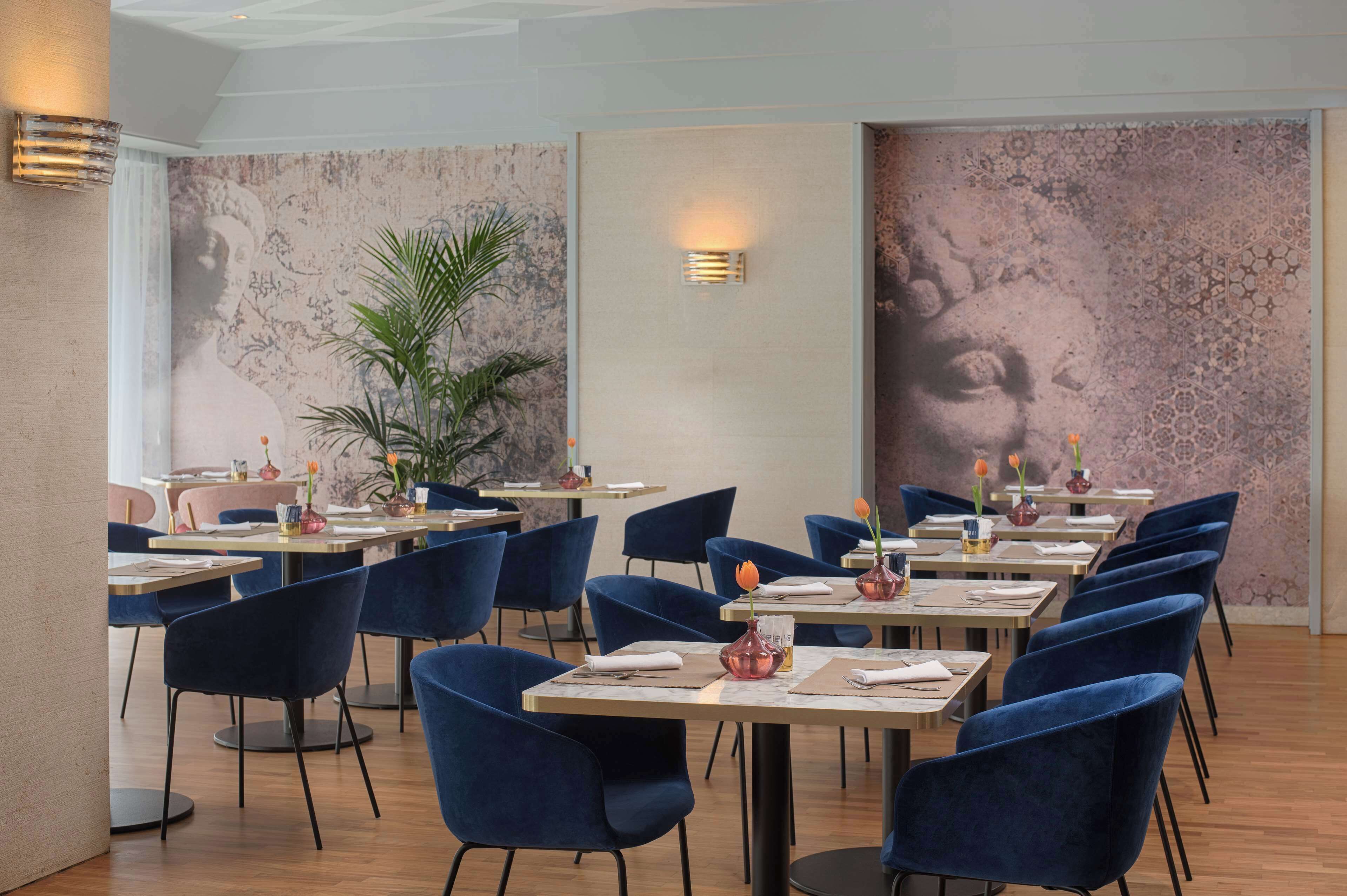 Un ristorante con sedie blu, tavoli di legno e vasi decorativi.