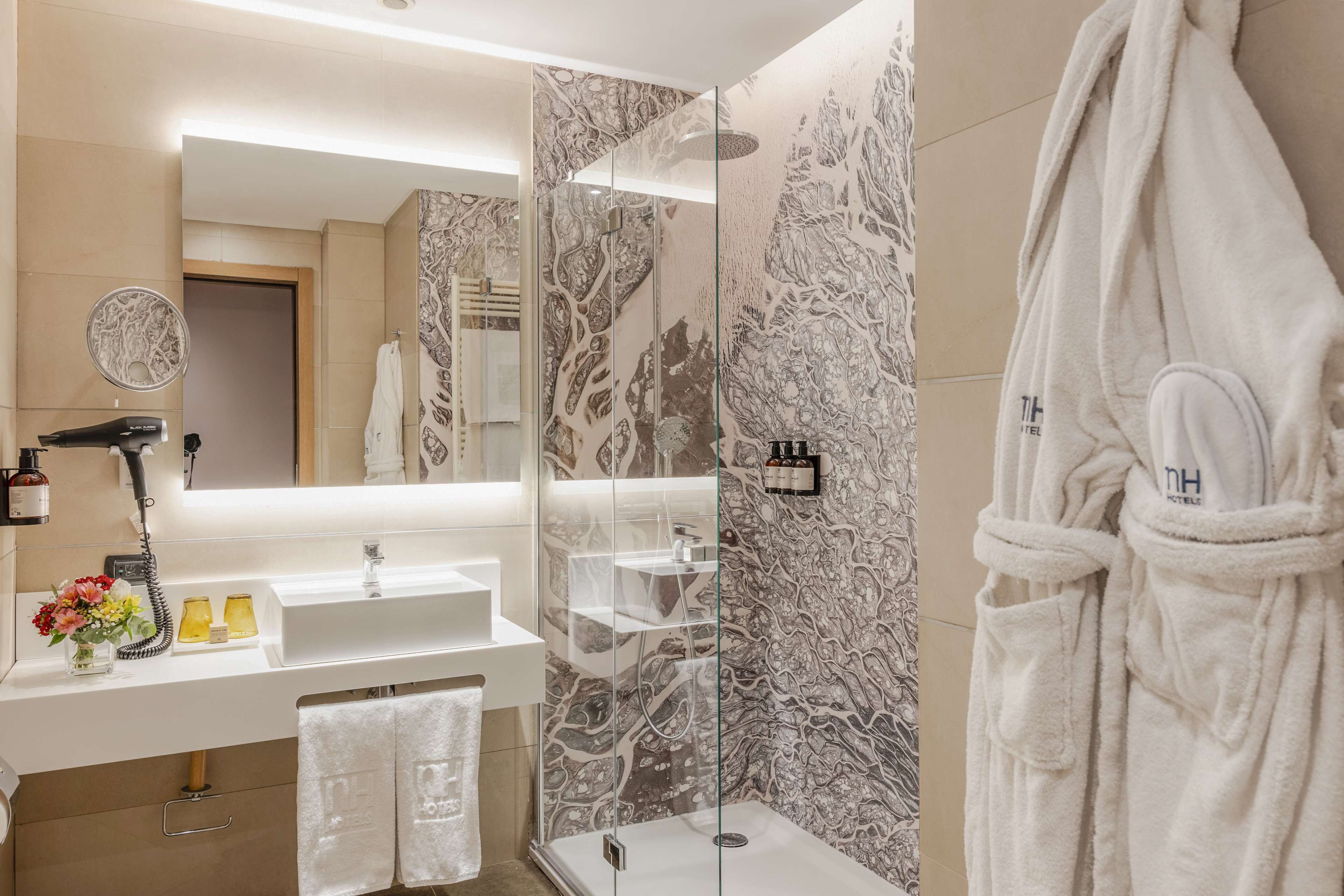Un bagno moderno con doccia vetro, lavandino bianco e uno specchio grande.