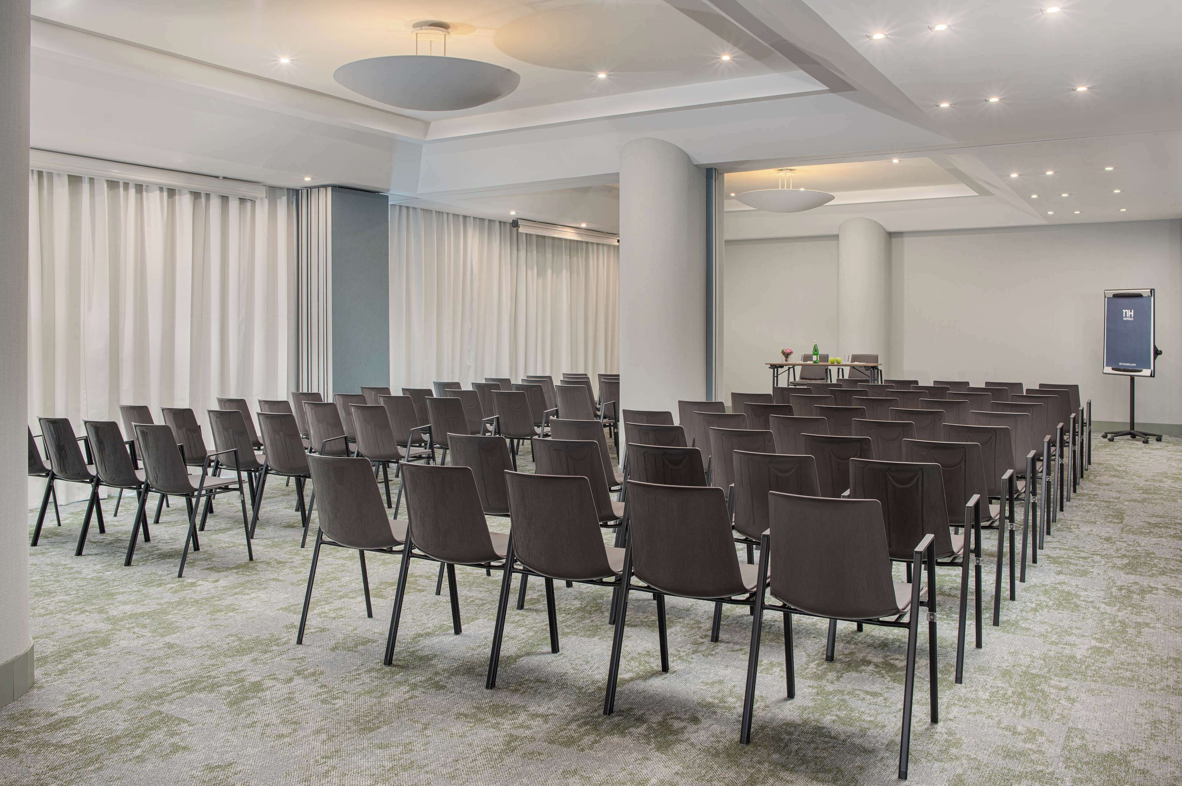 A conference room with rows of chairs, a projector screen, and a carpeted floor.