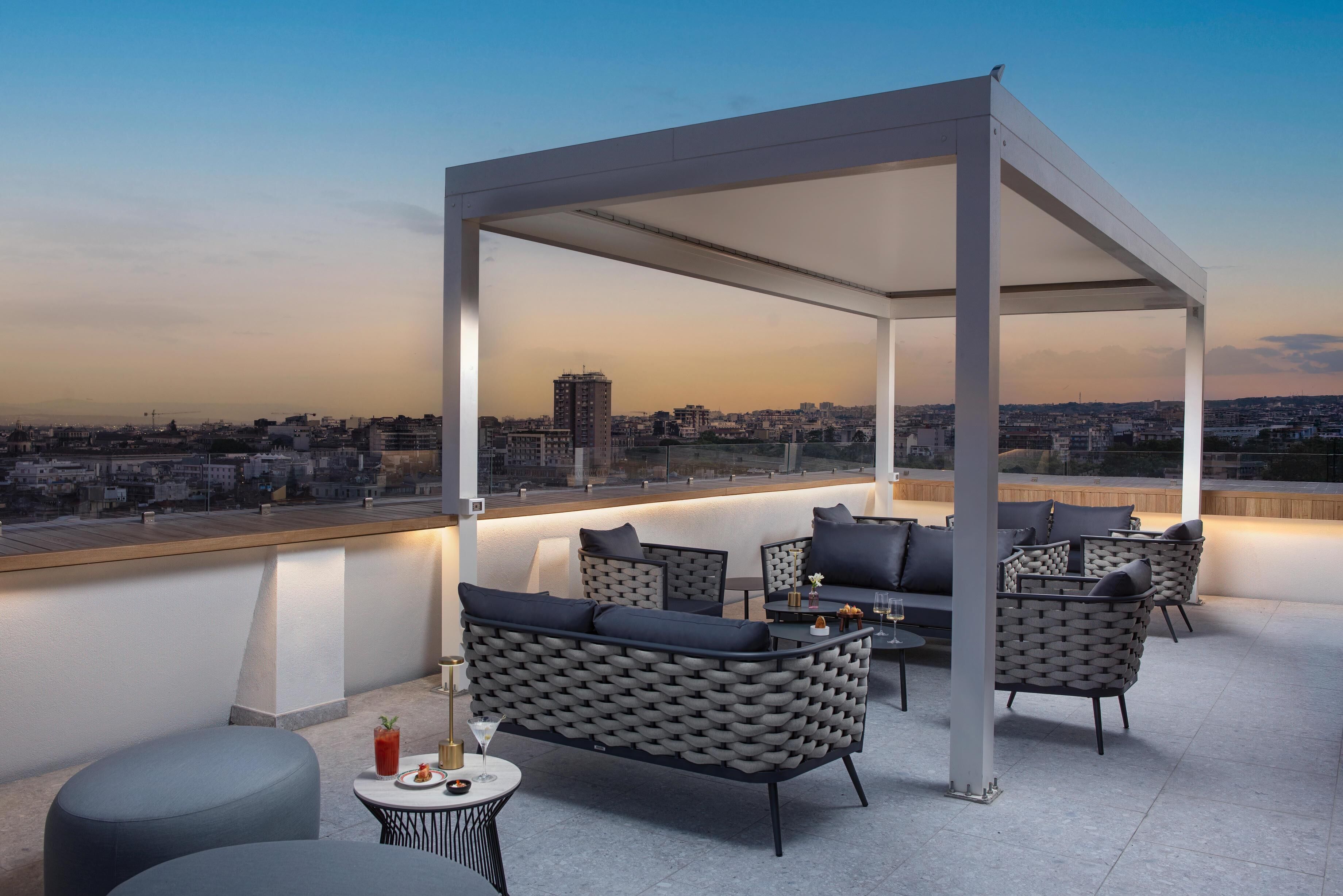A rooftop terrace with a covered seating area, a bar, and a view of the cityscape.