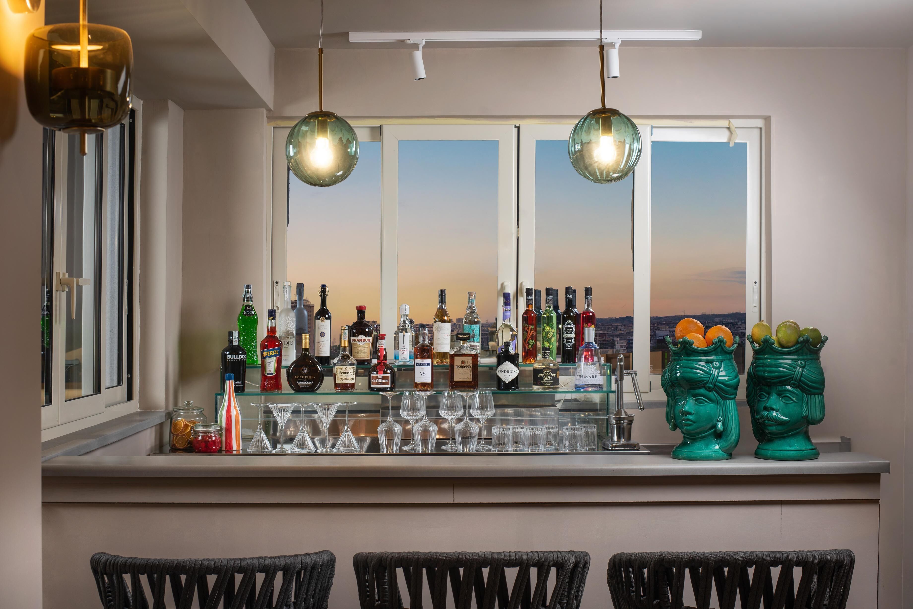 Zona de bar con botellas, vasos y jarrones decorativos.
