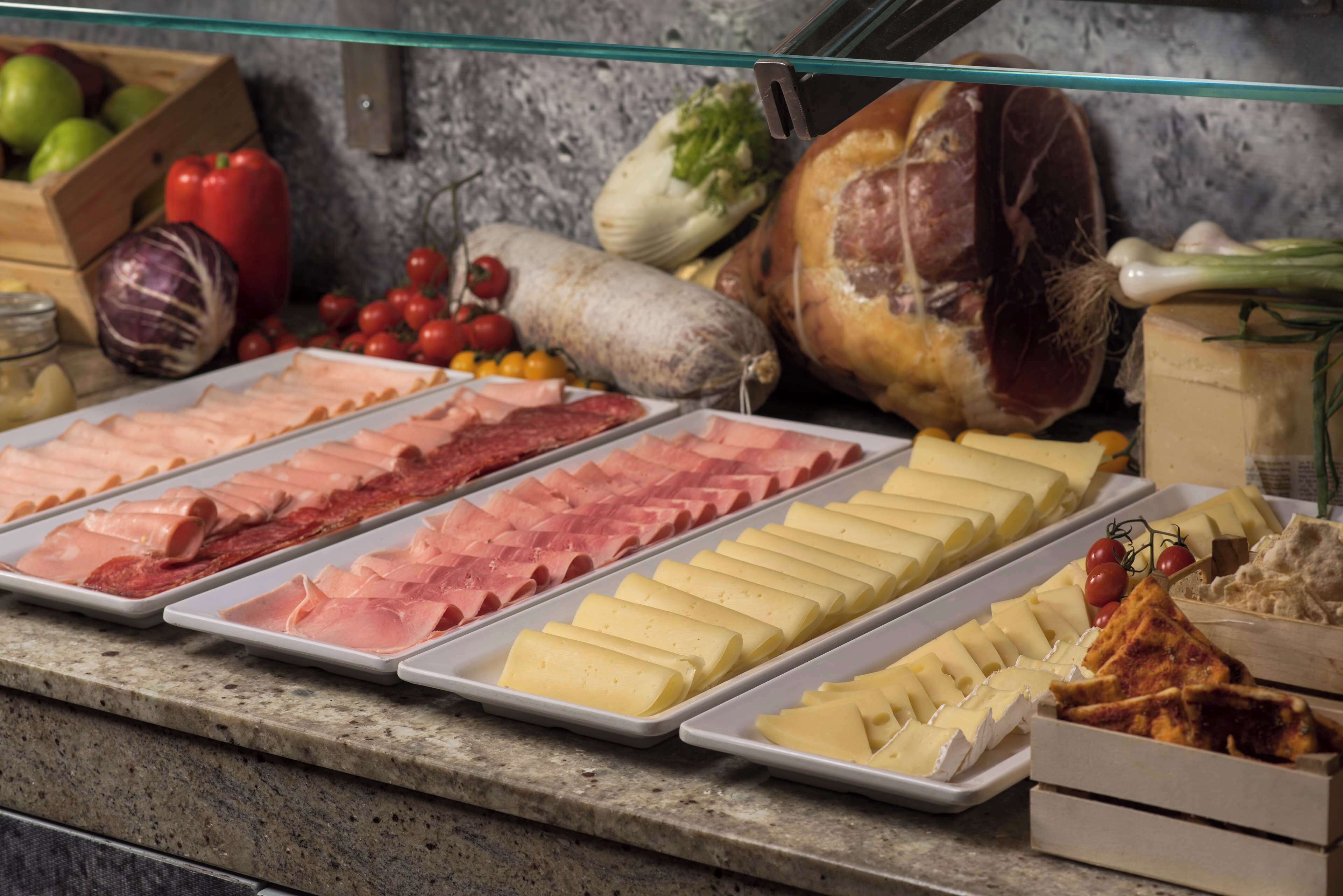 A buffet with various meats, cheeses, and vegetables.