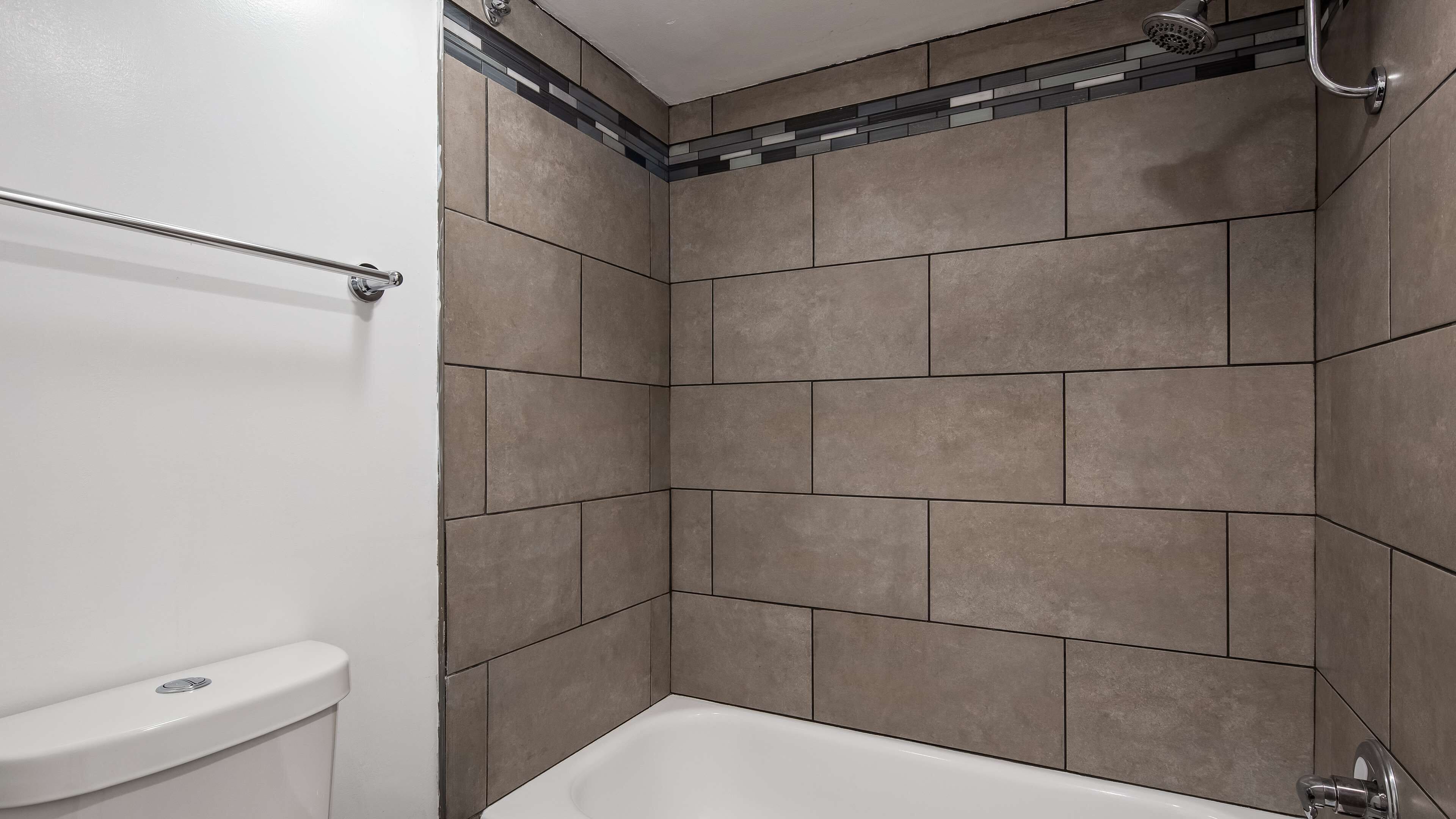 A bathroom with a bathtub, a toilet, and tiled walls.