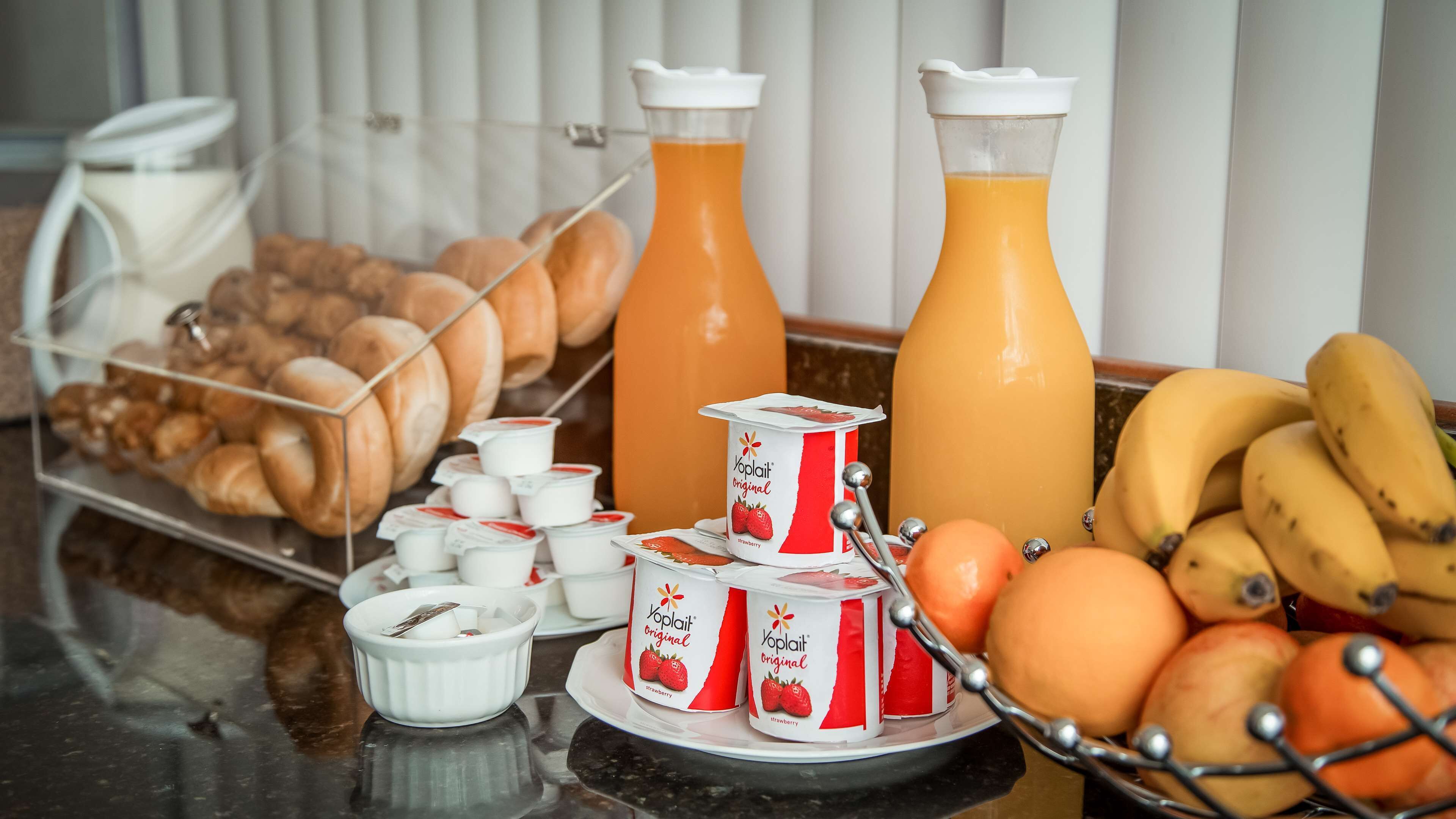 Un bufé de desayuno con pasteles, yogur, zumo y frutas.