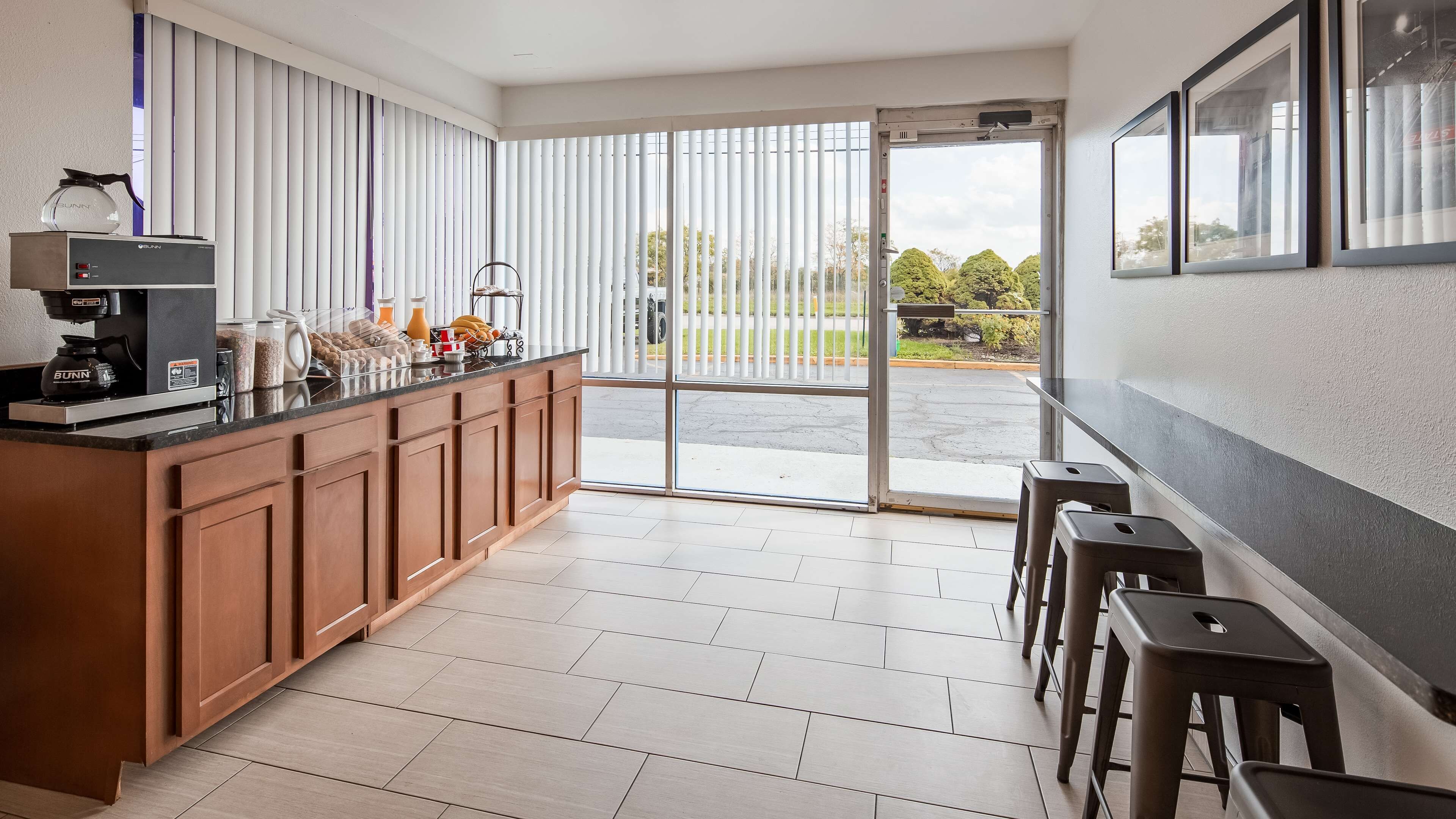 A modern kitchen with a built-in coffee machine, a breakfast bar, and a sliding glass door leading to a patio.