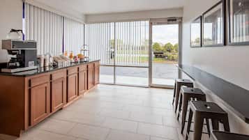 A modern kitchen with a built-in coffee machine, a breakfast bar, and a sliding glass door leading to a patio.
