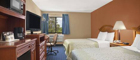 A hotel room with a desk, television, two beds, a chair, and a window with curtains.