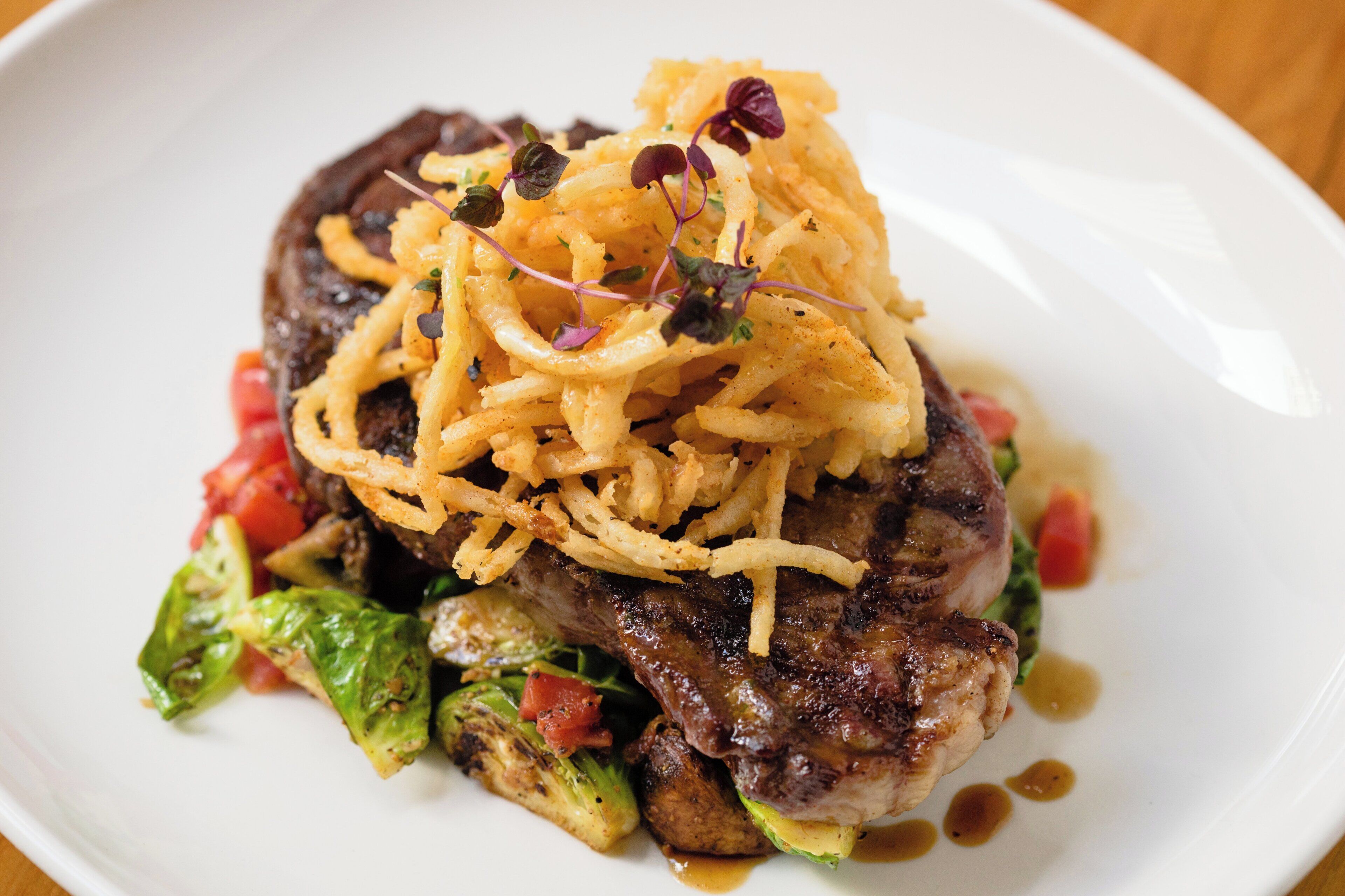 A plate with a steak, vegetables, and a garnish.