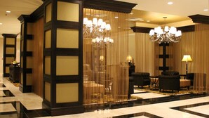 A hotel lobby with a checkered floor, dark wooden paneling, chandeliers, and seating areas. - InterContinental New Orleans by IHG (New Orleans)