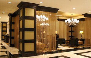 A hotel lobby with a checkered floor, dark wooden paneling, chandeliers, and seating areas. - InterContinental New Orleans by IHG (New Orleans)
