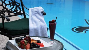 Angolo piscina con tavolo, un piatto di frutta e una bevanda.