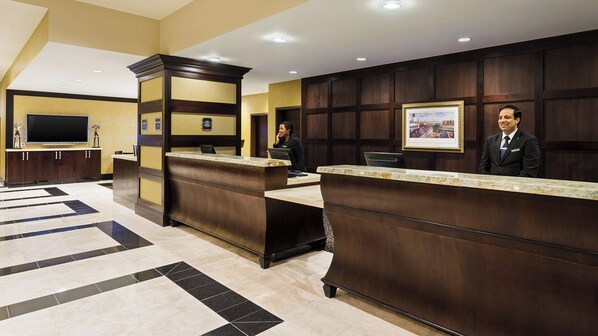 A hotel reception area with a marble reception desk, a flat-screen TV, and a framed picture on the wall.