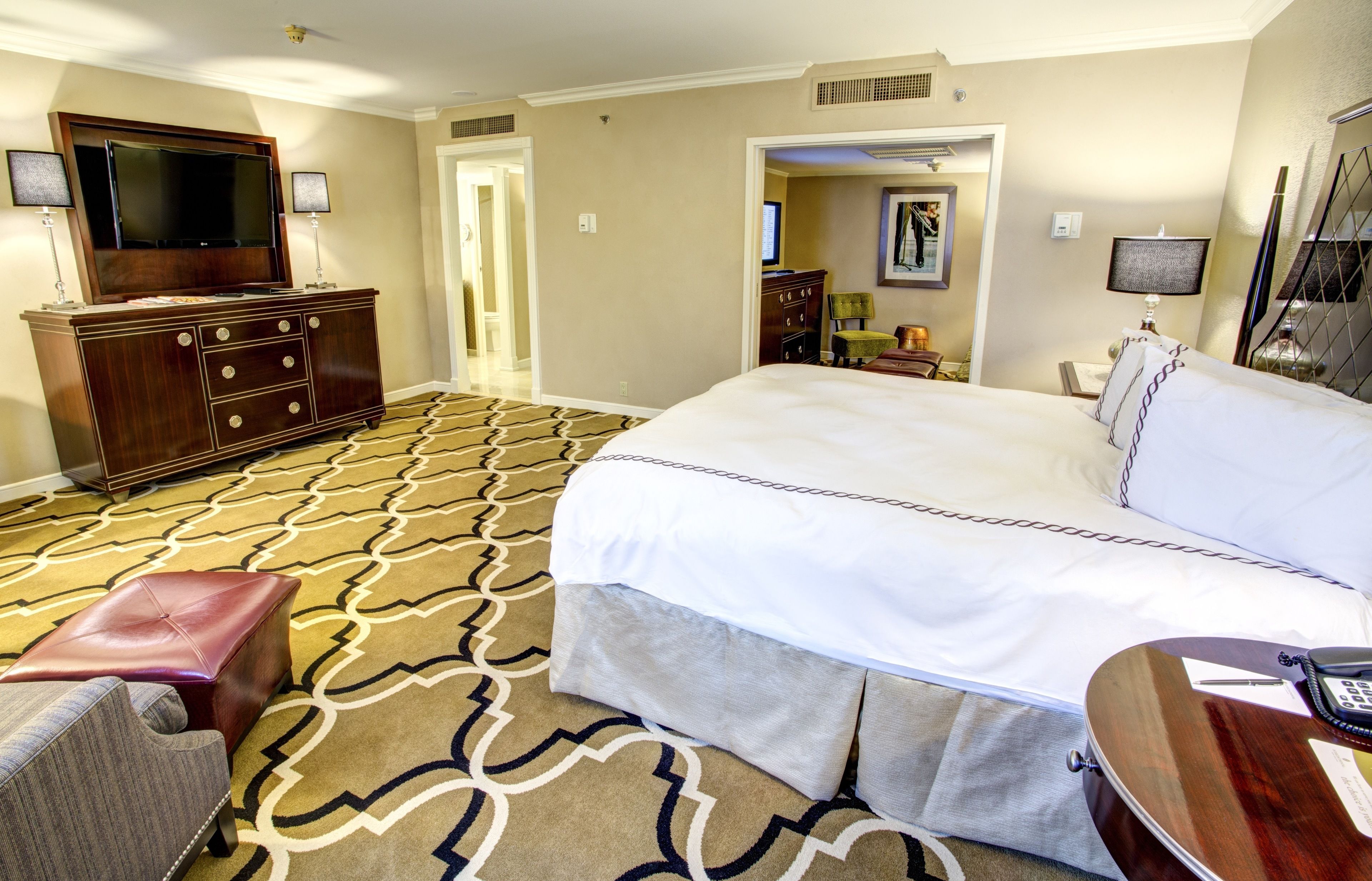 Una habitación de hotel con una cama grande, televisión, cómoda y piso alfombrado.
